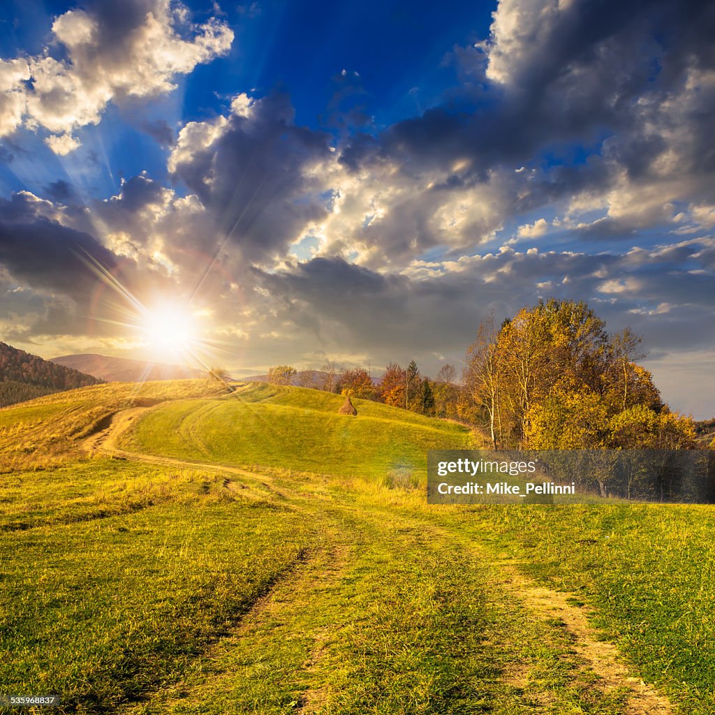 Path on hillside meadow in mountain at sunset