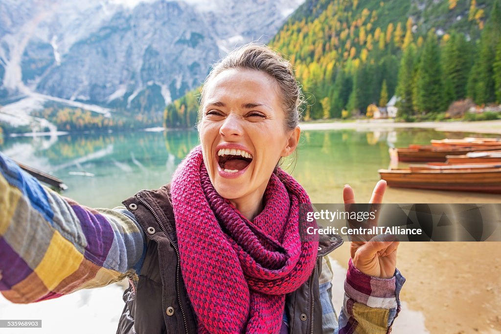 Smiling young woman making selfie on lake braies, italy