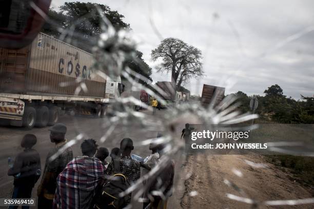 Street vendors are seen through a bus windscren bullet hole alongside the Mozambican Main North South road on May 27, 2016 at Nhamapaza in the...