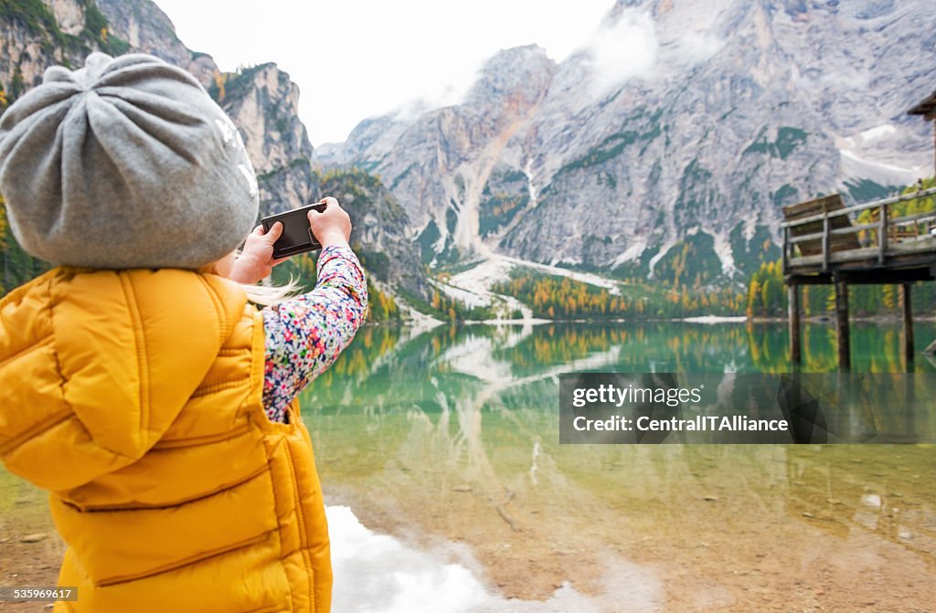 Child taking photo of lake braies, italy. rear view