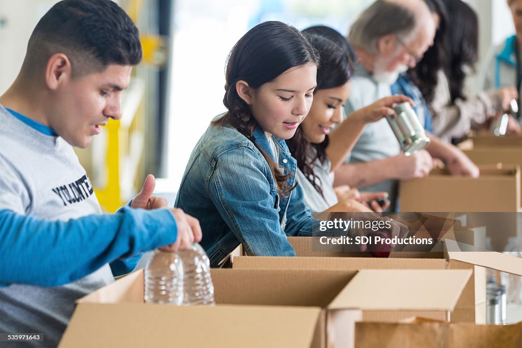 Diverse group of volunteers sorting food donations into boxes