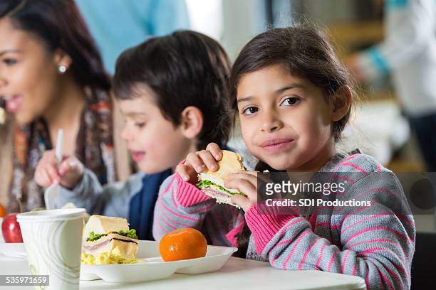 young hispanic family eating meal at neighborhood soup kitchen - boy gift stockfoto's en -beelden