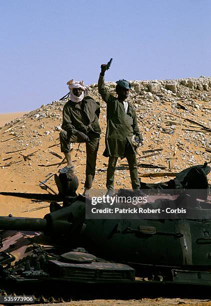 Two soldiers with the Forces Armees Nationales Chadiennes , or National Army of Chad, stand atop a captured Libyan military tank in Faya-Largeau. The...