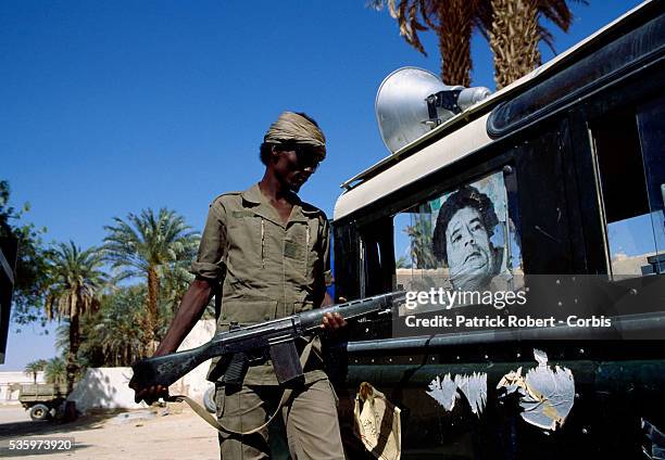 Soldier with the Forces Armees Nationales Chadiennes , or National Army of Chad, toys with a photograph of Colonel Muammar al-Qaddafi on the side of...
