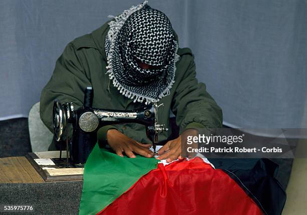 Palestinian demonstrator sews a Palestinian Liberation Organization flag before a protest during the first Intifada. Violence broke out after rebel...