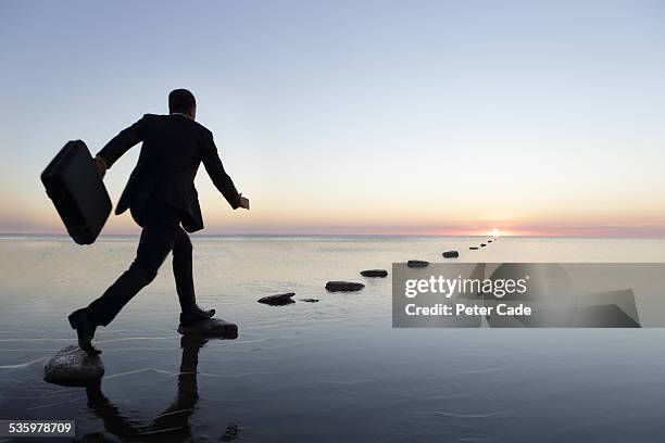 man at sunset in suit , running over steppingstone - career path stock pictures, royalty-free photos & images