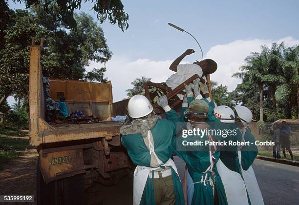 Zairean men in protective clothing and gloves lift the body of an Ebola virus victim from the back of a dump truck to be buried. The 1995 Ebola...