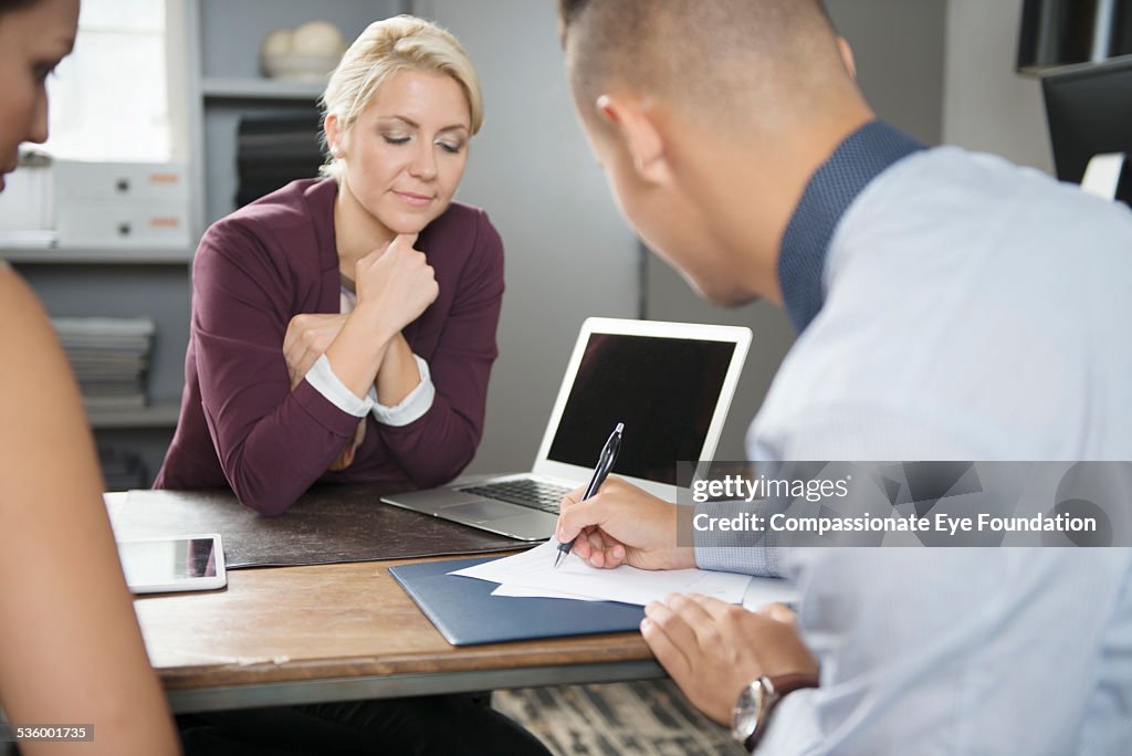 Couple signing documents with financial adviser