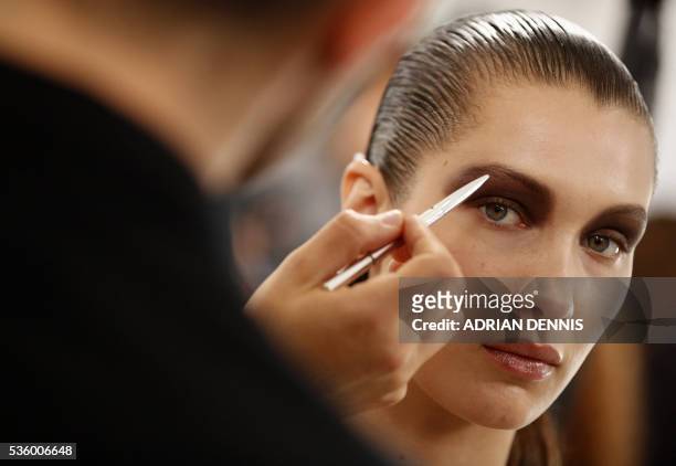 Model Bella Hadid waits as a make-up artist applies finishing touches to her eyebrow backstage ahead of the Christian Dior Cruise fashion show at...