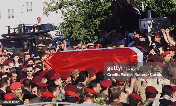 Bashar al-Assad, son and successor of the late Pr-esident, walking behind his father's coffin, rais-es his fist to greet the crowd.