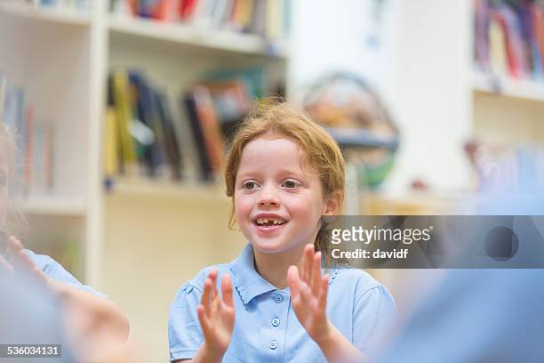 jeune fille de l'école souriant et taper dans les mains - enfant chant classe photos et images de collection