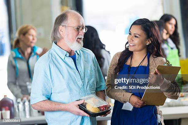 alter mann spricht mit freiwilligen in community food bank - depression bread line stock-fotos und bilder