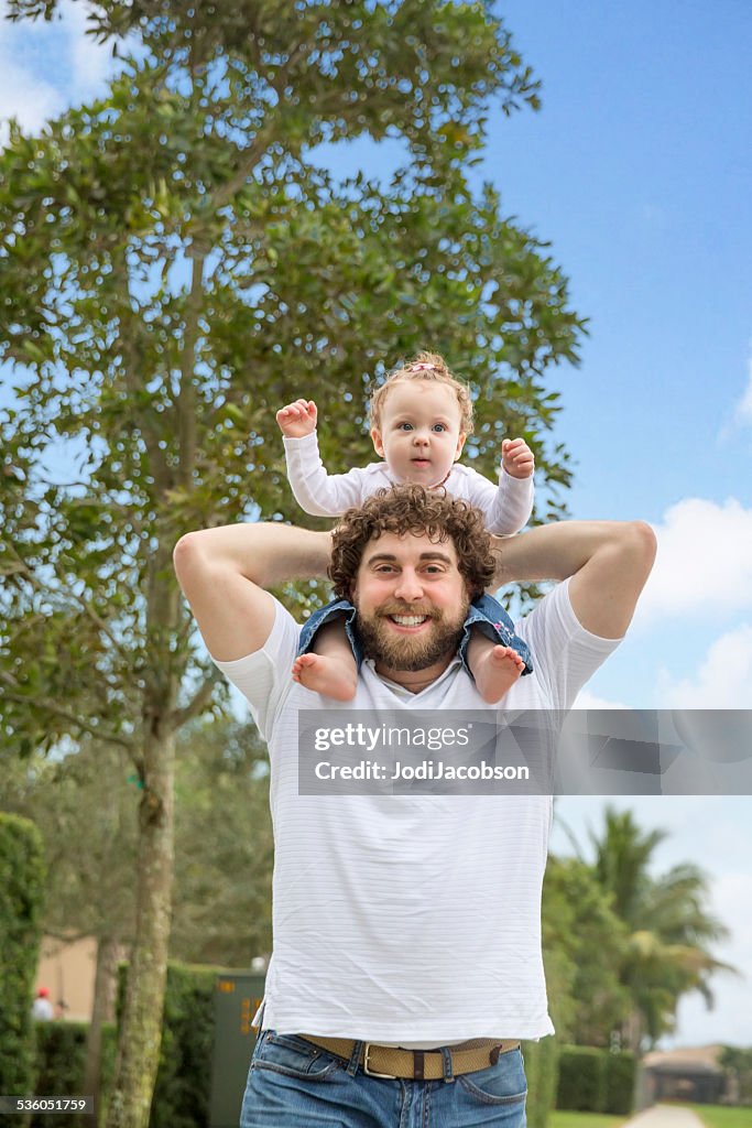 Caucasian father holding his baby daughter on his shoulders