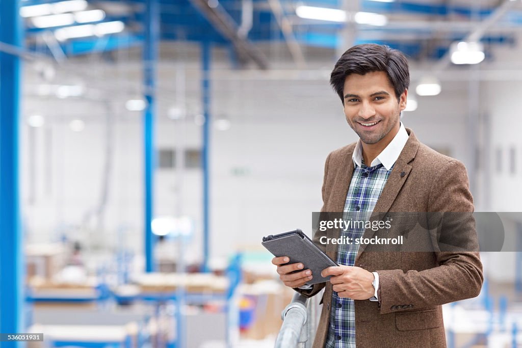 Happy young businessman with digital tablet in warehouse