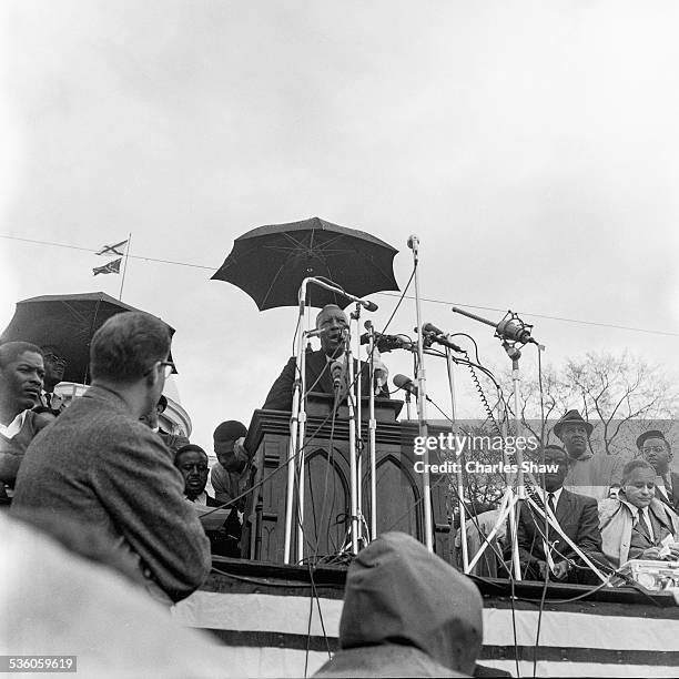 At the end of the Selma to Montgomery March, as the rain falls, Civil Rights and union leader A Philip Randolph speaks to the assembled marchers and...