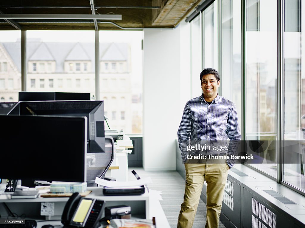 Smiling businessman standing at window in office