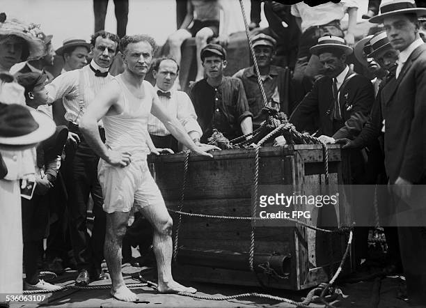 Illusionist and escape artist Harry Houdini performs his famous stunt whereby he was submerged in the East River in a crate, New York City, 7th July...