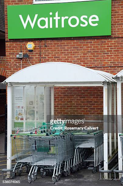 Waitrose sign and supermarket trolleys, Haslemere, Surrey. Waitrose has a chain of well known and upmarket British supermarkets with 317 stores in...