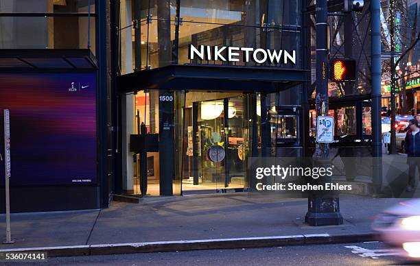 An urban Niketown storefront and sign in downtown Seattle, Washington at night. The windows and logo are glowing from across a busy street.