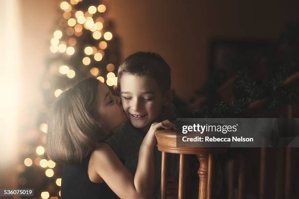 girl kissing boy's cheek at christmas - boy girl kissing stock pictures, royalty-free photos & images