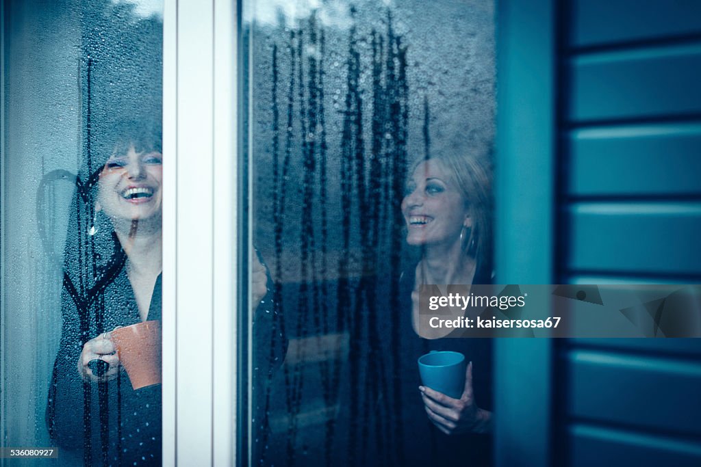 Two Happy women laughing behind window