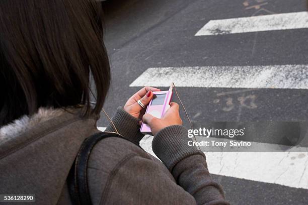 Woman with iPod walks on a crosswalk on a city street.