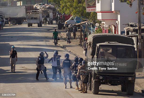 United Nations soldier, left, directs Haitian police as they arrest and slap a protester. A popular teacher was grabbed from a "Bond", a slow-moving...