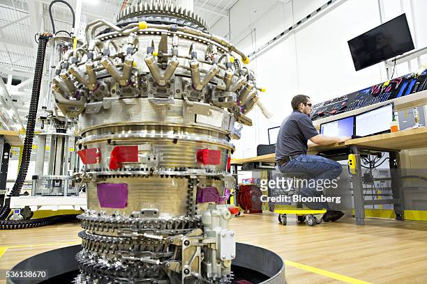 The core of a LEAP 1A aircraft engine sits as an assembly technician works on a desktop computer at the General Electric Aviation jet engine facility...