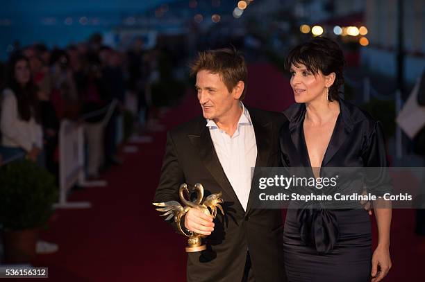 Benoit Magimel poses with actress Juliette Binoche as he awarded best actor during the closing Ceremony of the 29th Cabourg Romantic Film Festival on...