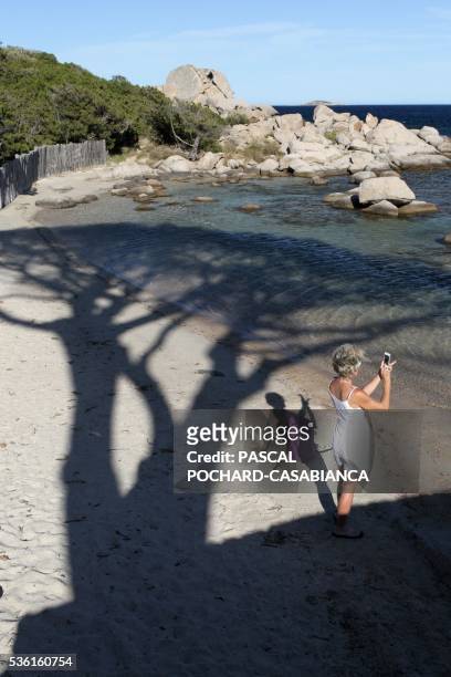 Woman takes a photo on Palombaggia beach on May 30, 2016 in Porto Vecchio, on the French Mediterranean island of Corsica.