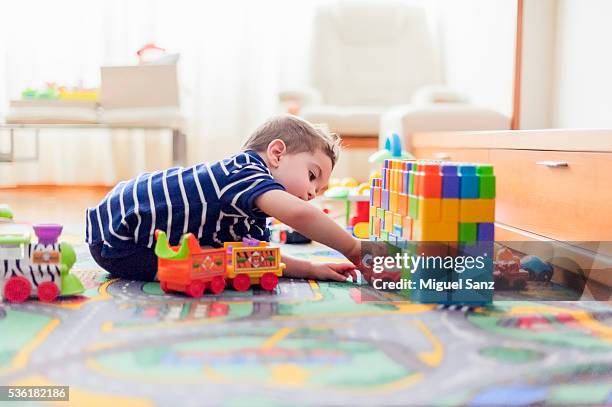 little boy, 2 years, playing with small cars and toys at home - children playing with toys stockfoto's en -beelden