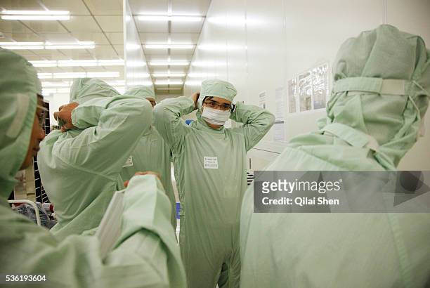 Employees put on clean suits before entering the wafer FAB of Semiconductor Manufacturing International Corp in Shanghai, China on 18 February, 2011....