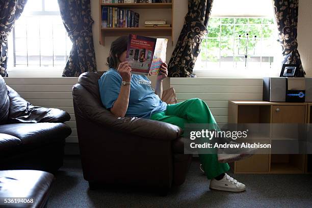 Prisoner reads a magazine in the lounge of one of the residential units. HM Prison Styal is a Closed Category prison for female adults and young...