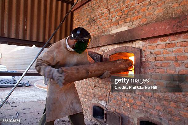 Young Brazilian man stoking a fire used to dry grain on a large soya and maize farm. Brazil is the largest producer of Sugar and Beef, then second...