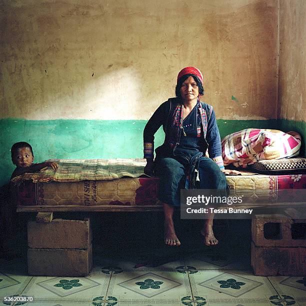 An Aini ethnic minority woman sits on a bed with a young boy in her home in Xiang Dao Ya village. Costume styles in the past were identified by...