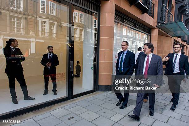 As businessmen walk past, staff at the Gagosian Art Gallery in Davies Street, Mayfair London stand in the window with a kneeling Hitler called La...