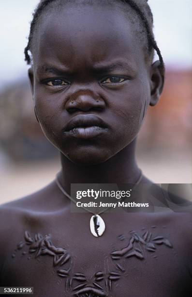 Young girl with deep ritual scarring on her chest and cowrie shell necklace. Ajiep, Bahr el Ghazal, Sudan.