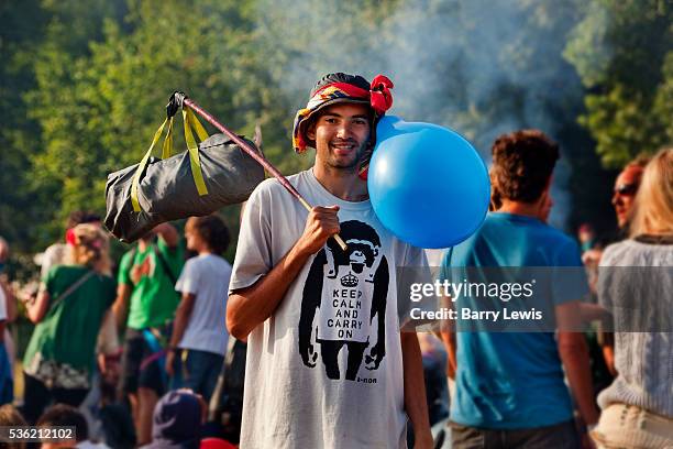 Man wearing balloon & Banksy T-shirt withe the slogan "Keep Calm and Carry On", the morning after in the stone circle, Glastonbury Festival 2010