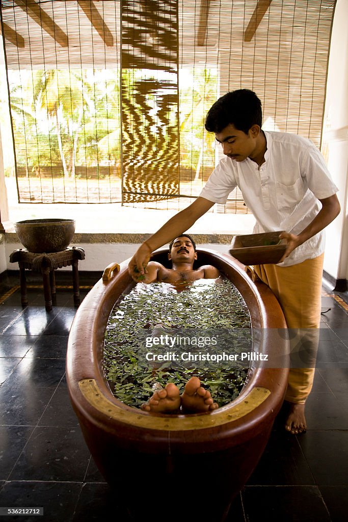 India - Ayurveda - A patient relaxes in a bath as part of an Ayurveda treatment