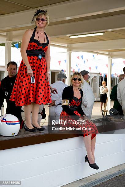 Two ladies in identical red & black polka dot dresses on the pit lane wall