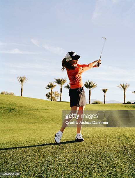 golfer swinging golf club - golf spielen stock-fotos und bilder