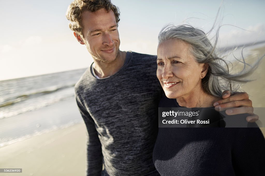 Mother and adult son walking on beach