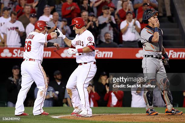 James McCann of the Detroit Tigers looks on as Kole Calhoun congratulates Mike Trout of the Los Angeles Angels of Anaheim after Trout hit a three-run...