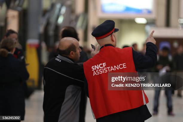 An employee of French state-owned rail operator SNCF helps a passenger at the Gare de Lyon railway station on June 1, 2016 in Paris, at the start of...