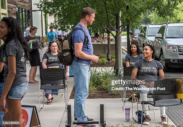 Volunteer Kari Scott, right, chats with a man passing by as Sidewalk Talk DC, a free listening project and community service, sets up in the Mosaic...