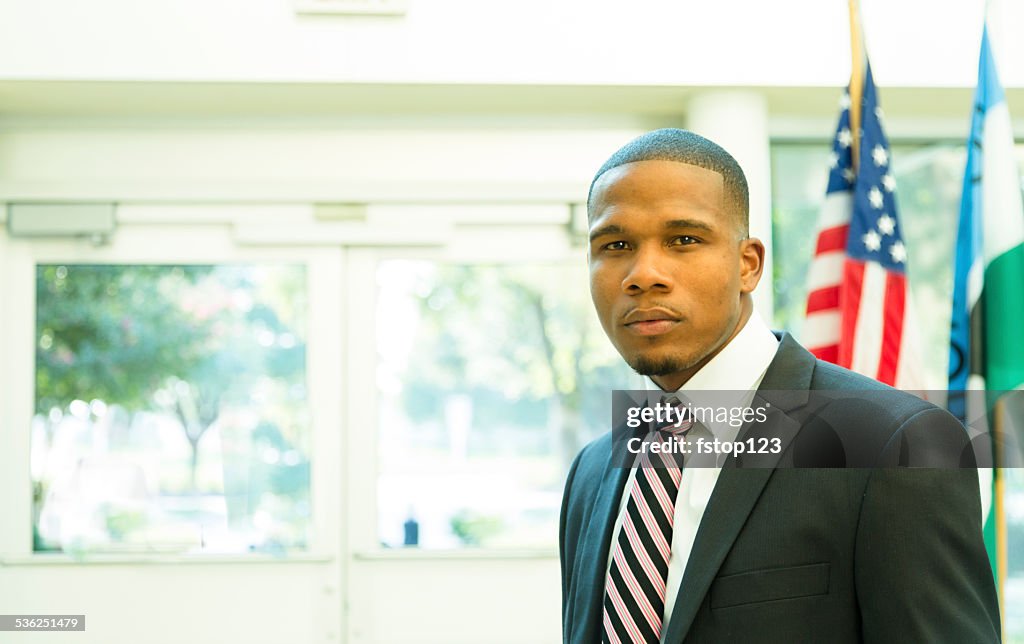 African descent attorney, politician in courthouse building. American flag. Suit.