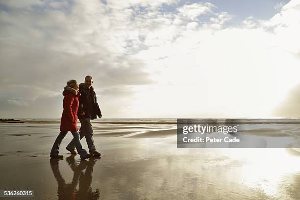 couple walking on beach , winter, low light. - walking side view stock-fotos und bilder