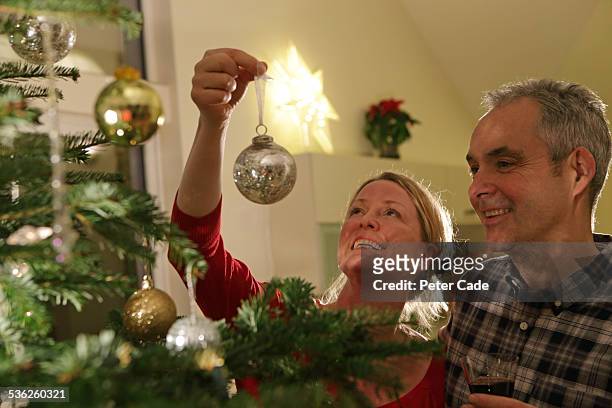couple getting the christmas tree ready . - christmas tree 50's stockfoto's en -beelden