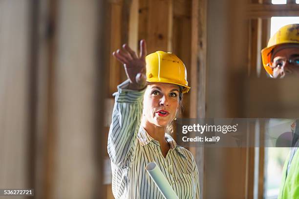 mature workers talking at construction site - female boss stockfoto's en -beelden