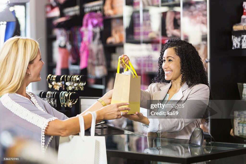 Freundliche Aushilfsverkäufer mit Kunden beim Check-out-Schalter